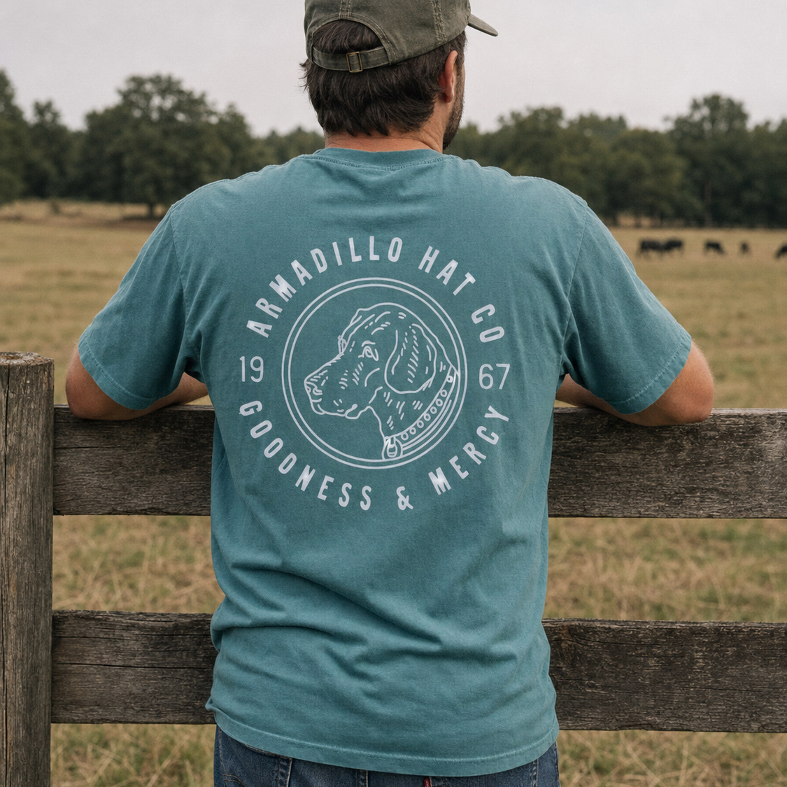 Man wearing the Bird Dog Tee in Blue Spruce at a pasture fence