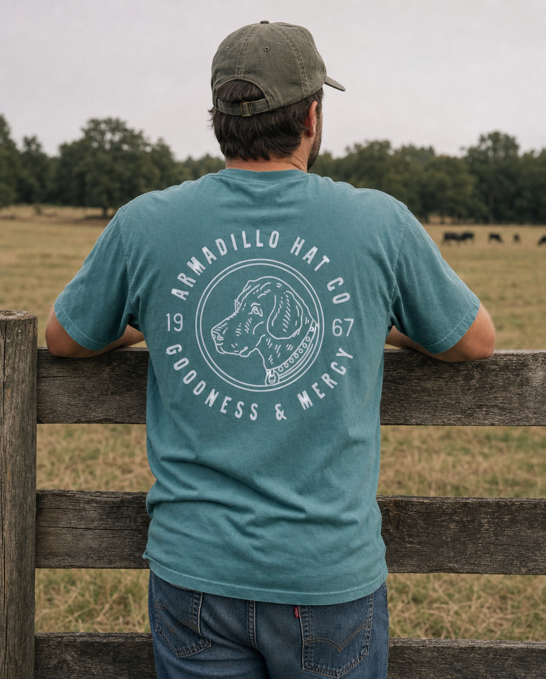 Man wearing the Bird Dog Tee in Blue Spruce at a pasture fence