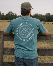 Man wearing the Bird Dog Tee in Blue Spruce at a pasture fence