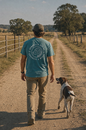 Man wearing the Bird Dog Tee walking a ranch road with a bird dog