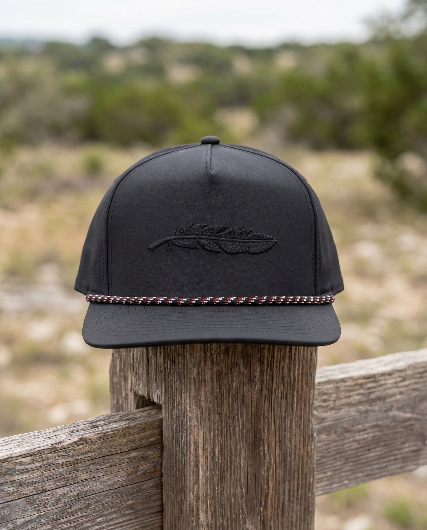 Blackbird rope snapback resting on a cedar fence post in the Texas hill country